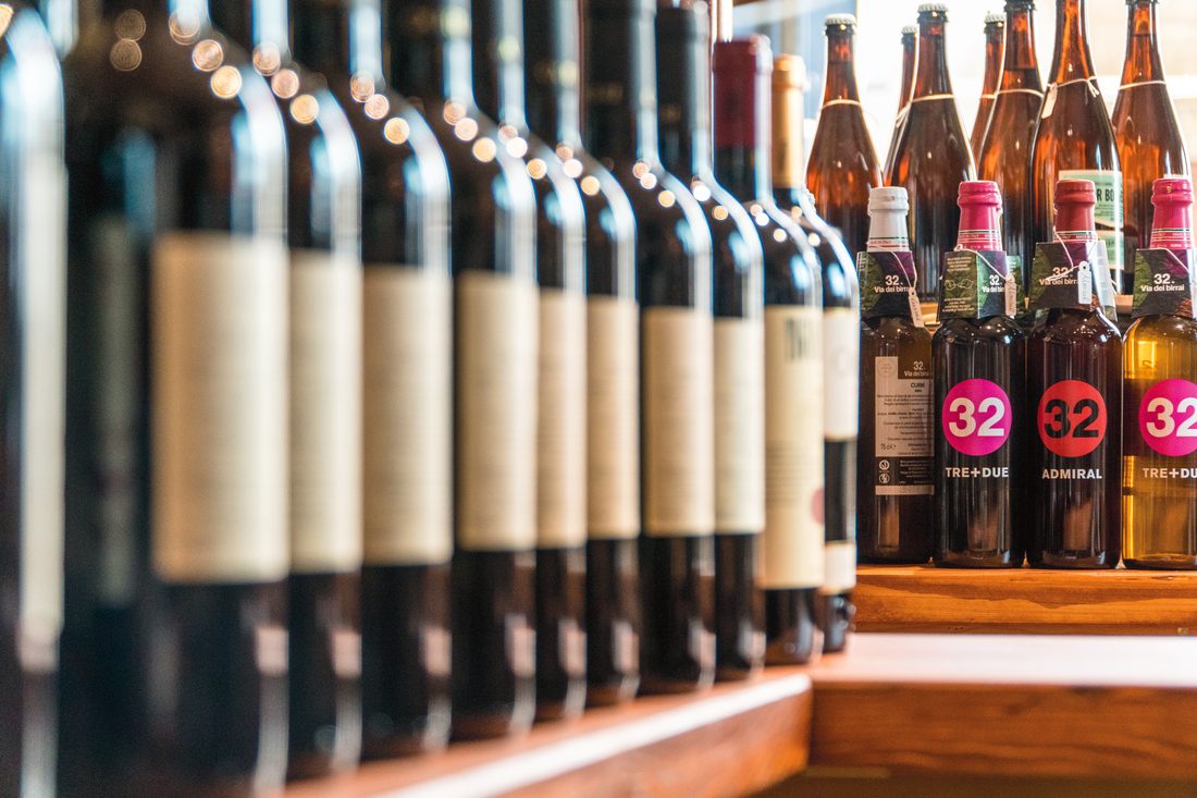 Bottiglie di vino ed etichette di birra artigianale nello scaffale dell'enoteca
