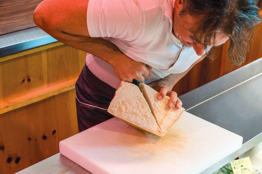 Taglio di una forma di formaggio stagionato in gastronomia Zanini